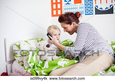 Mother holding cell phone to sons ear in bed View Large Photo Image Stock Image - Mother holding cell phone to sons ear in bed. Fotosearch