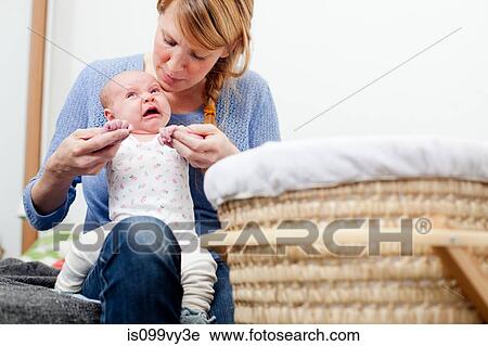 Stock Image - Mother holding upset newborn daughter. Fotosearch