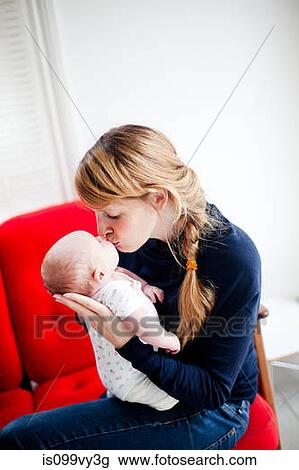 Stock Image - Mother kissing newborn daughter. Fotosearch