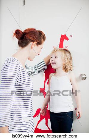 Picture - Mother measuring daughters height on height chart. Fotosearch
