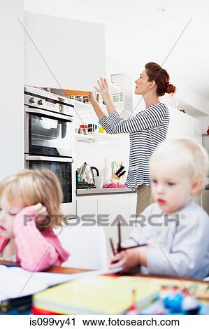 Mother opening kitchen cupboard View Large Photo Image Stock Image - Mother opening kitchen cupboard. Fotosearch