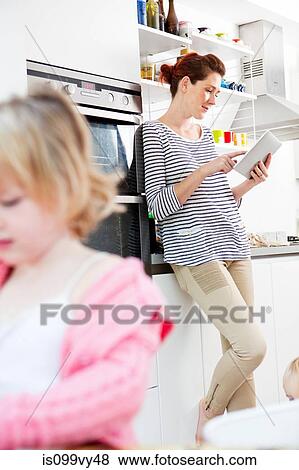 Mother using digital tablet, daughter in foreground View Large Photo Image Stock Photo - Mother using digital tablet, daughter in foreground. Fotosearch