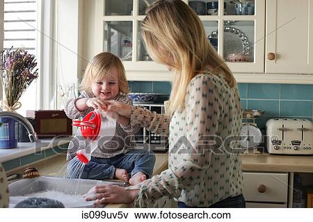 Mother washing up, daughter pouring water View Large Photo Image Stock Photo - Mother washing up, daughter pouring water. Fotosearch