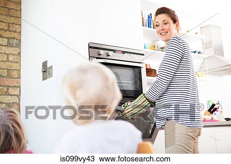 Mother wearing oven gloves opening oven View Large Photo Image Stock Image - Mother wearing oven gloves opening oven. Fotosearch