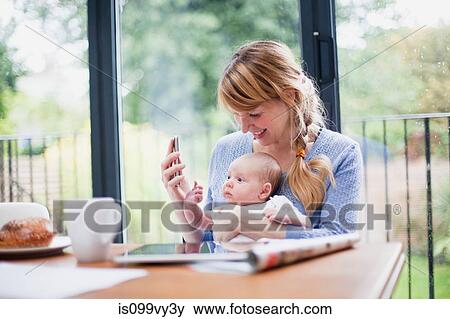 Mother with cell phone and newborn daughter View Large Photo Image Stock Photo - Mother with cell phone and newborn daughter. Fotosearch