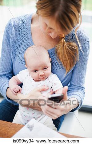 Mother with newborn baby and cell phone View Large Photo Image Picture - Mother with newborn baby and cell phone. Fotosearch