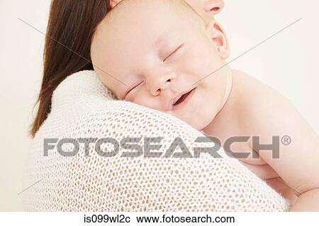 Stock Image - Mother with newborn baby sleeping on shoulder. Fotosearch
