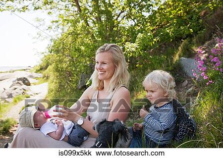 Stock Image - Mother with toddler feeding newborn baby. Fotosearch
