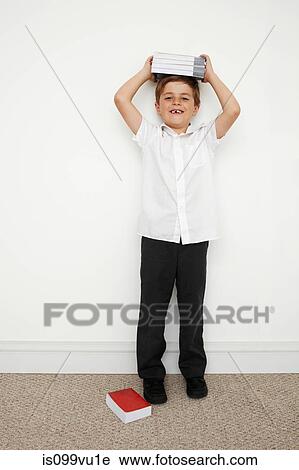 Schoolboy holding books on his head View Large Photo Image Stock Image - Schoolboy holding books on his head. Fotosearch
