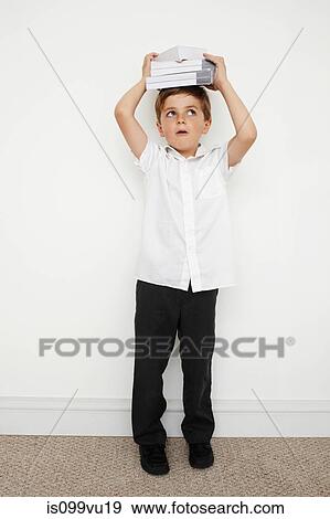 Schoolboy holding books on his head View Large Photo Image Stock Photo - Schoolboy holding books on his head. Fotosearch