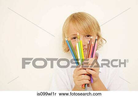 Stock Photography - Schoolboy holding bunch of colouring pencils. Fotosearch