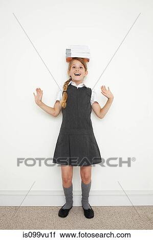 Stock Image - Schoolgirl balancing books on her head. Fotosearch