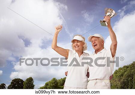 Senior couple holding tennis trophy and cheering View Large Photo Image Stock Image - Senior couple holding tennis trophy and cheering. Fotosearch