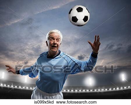 Stock Image - Senior man playing football. Fotosearch