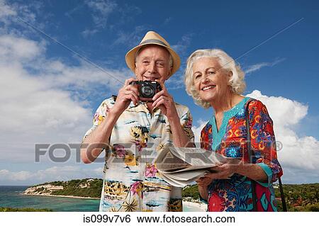 Stock Photograph - Senior tourist couple with camera and map. Fotosearch