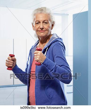 Stock Image - Senior woman holding hand weights. Fotosearch