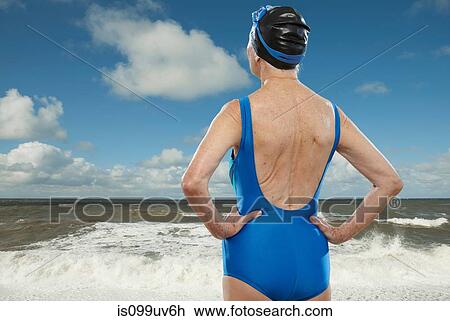 Stock Image - Senior woman wearing swimsuit looking towards sea. Fotosearch