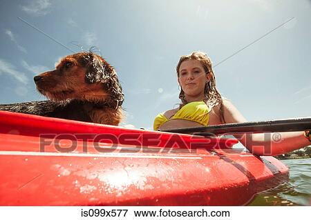 Stock Photo - Teenage girl and pet dog in kayak. Fotosearch
