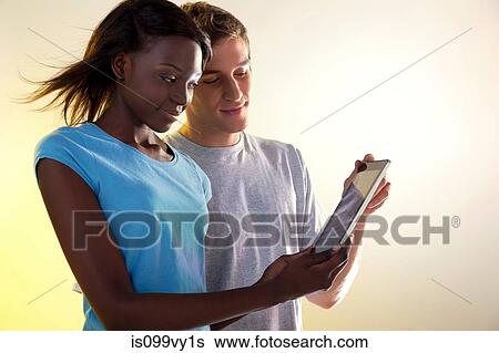 Teenage girl and young man looking at digital tablet View Large Photo Image Stock Photograph - Teenage girl and young man looking at digital tablet. Fotosearch