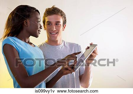 Stock Photo - Teenage girl and young man using digital tablet. Fotosearch