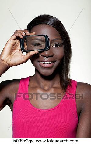 Teenage girl holding smartphone over eye View Large Photo Image Stock Photo - Teenage girl holding smartphone over eye. Fotosearch