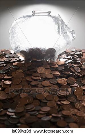 Stock Image - Transparent piggy bank on top of pile of coins. Fotosearch