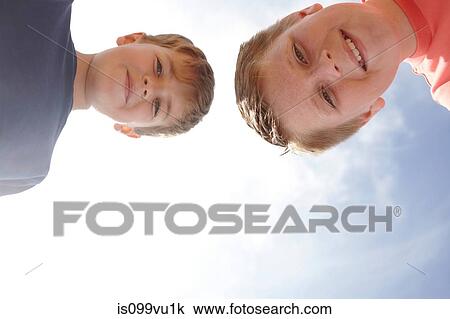 Stock Image - Two boys looking at camera, viewed from below. Fotosearch