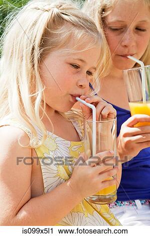 Two girls drinking orange juice View Large Photo Image Stock Image - Two girls drinking orange juice. Fotosearch