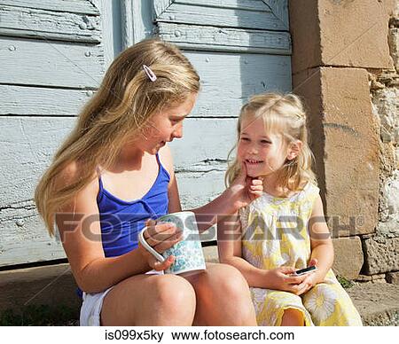 Stock Photo - Two sisters, one touching others face. Fotosearch
