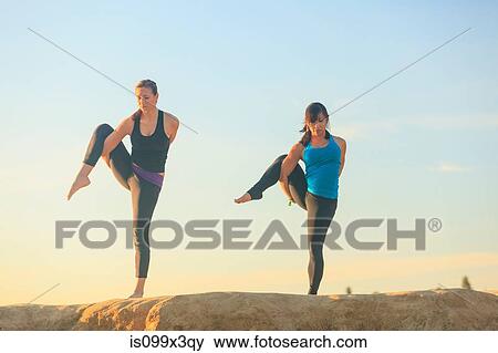 Two women practising yoga on top of a rock View Large Photo Image Stock Photo - Two women practising yoga on top of a rock. Fotosearch