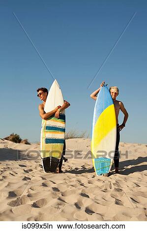Two young men standing behind surfboards on beach View Large Photo Image Picture - Two young men standing behind surfboards on beach. Fotosearch