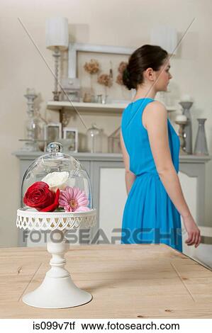 Stock Image - Woman and cake stand with flowers in kitchen. Fotosearch