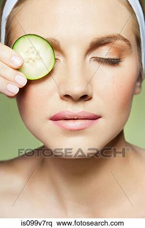 Woman covering eye with piece of cucumber View Large Photo Image Stock Photography - Woman covering eye with piece of cucumber. Fotosearch