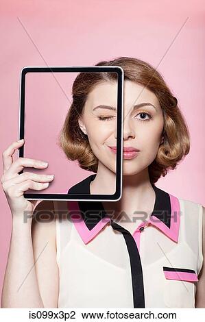 Stock Image - Woman covering half her face with digital tablet. Fotosearch