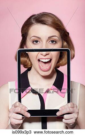 Stock Image - Woman covering half her face with digital tablet. Fotosearch