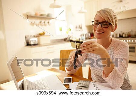 Picture - Woman cutting credit card with scissors. Fotosearch