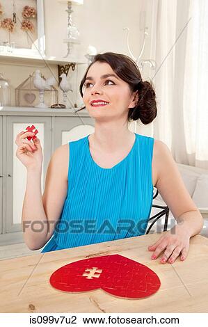 Woman doing heart shaped jigsaw puzzle holding piece View Large Photo Image Stock Image - Woman doing heart shaped jigsaw puzzle holding piece. Fotosearch