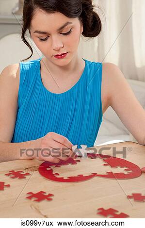 Stock Photo - Woman doing heart shaped jigsaw puzzle. Fotosearch
