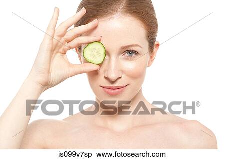 Woman holding a cucumber slice to her eye View Large Photo Image Stock Photography - Woman holding a cucumber slice to her eye. Fotosearch