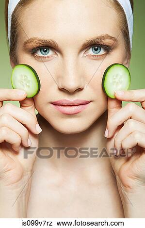 Woman holding two pieces of cucumber View Large Photo Image Stock Photo - Woman holding two pieces of cucumber. Fotosearch