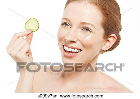 Woman holding up a cucumber slice View Large Photo Image Picture - Woman holding up a cucumber slice. Fotosearch