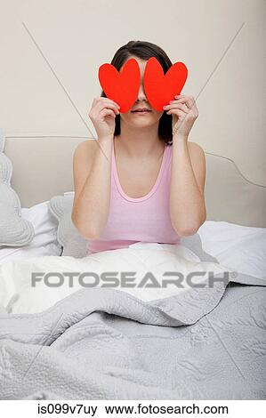 Woman in bed holding heart shapes over eyes View Large Photo Image Stock Photo - Woman in bed holding heart shapes over eyes. Fotosearch