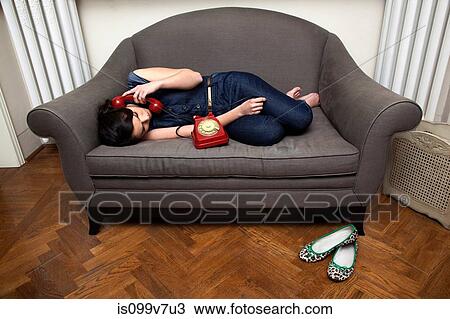 Stock Image - Woman lying on sofa on the telephone. Fotosearch
