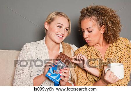 Stock Image - Woman offering friend chocolate. Fotosearch