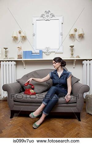 Woman on sofa picking up telephone handset View Large Photo Image Picture - Woman on sofa picking up telephone handset. Fotosearch