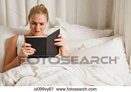 Stock Photo - Woman reading book in bed. Fotosearch