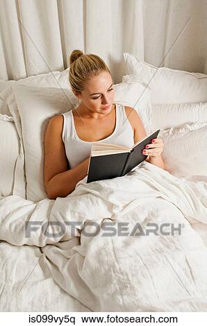 Stock Photography - Woman reading book in bed. Fotosearch