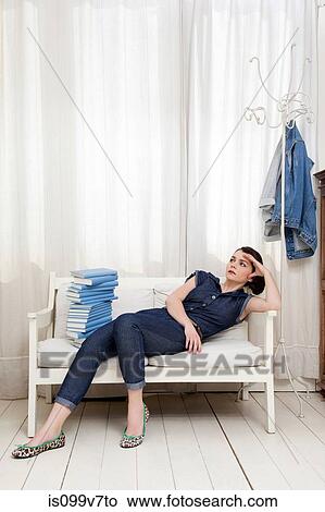Woman reclining on seat with pile of books View Large Photo Image Picture - Woman reclining on seat with pile of books. Fotosearch