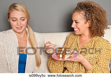 Picture - Woman staring at friend eating cake. Fotosearch