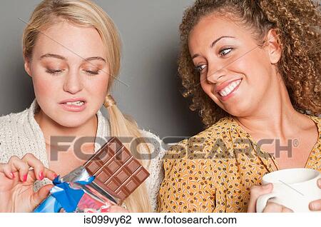 Woman staring at friend holding chocolate View Large Photo Image Stock Image - Woman staring at friend holding chocolate. Fotosearch